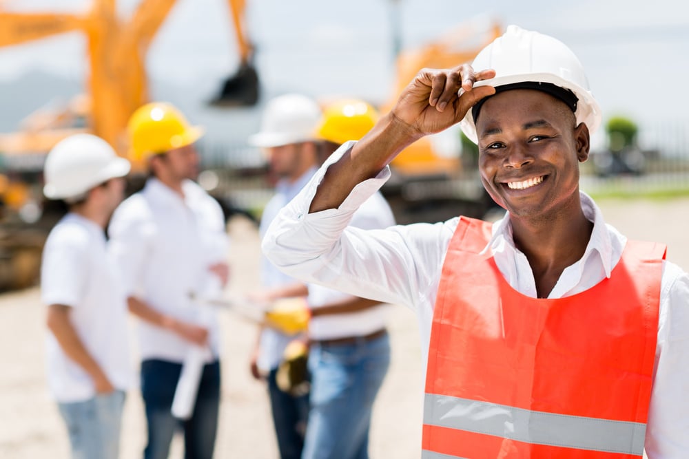 Happy male architect at a building site wearing a helmet