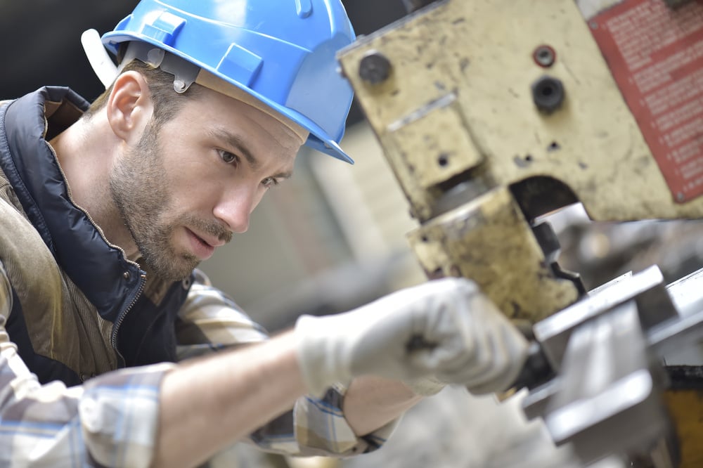 Industrial worker working on machine in HVAC parts factory